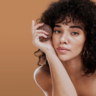 Person with curly hair holding a RELAX shampoo bar