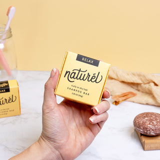 Hand holding a yellow RELAX shampoo bar box